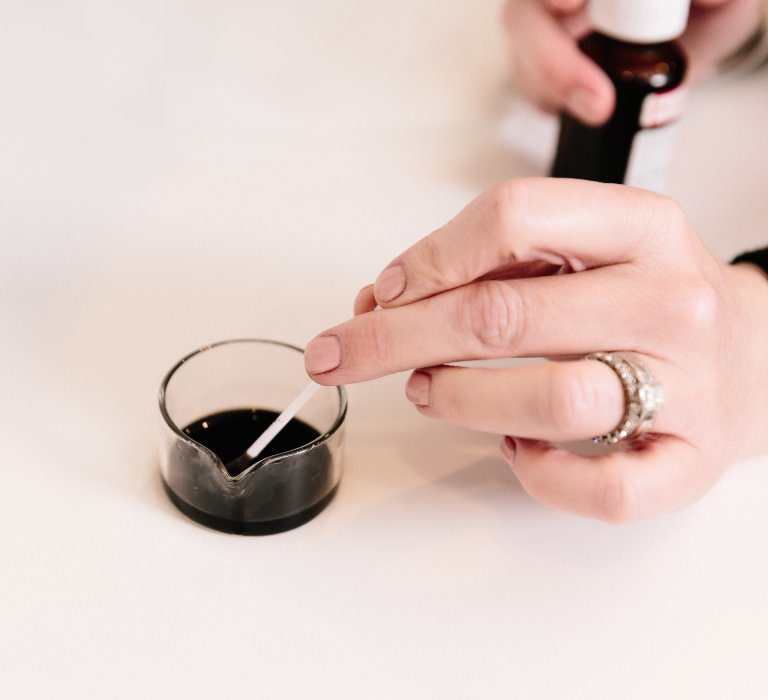 A woman dipping something in a dark liquid