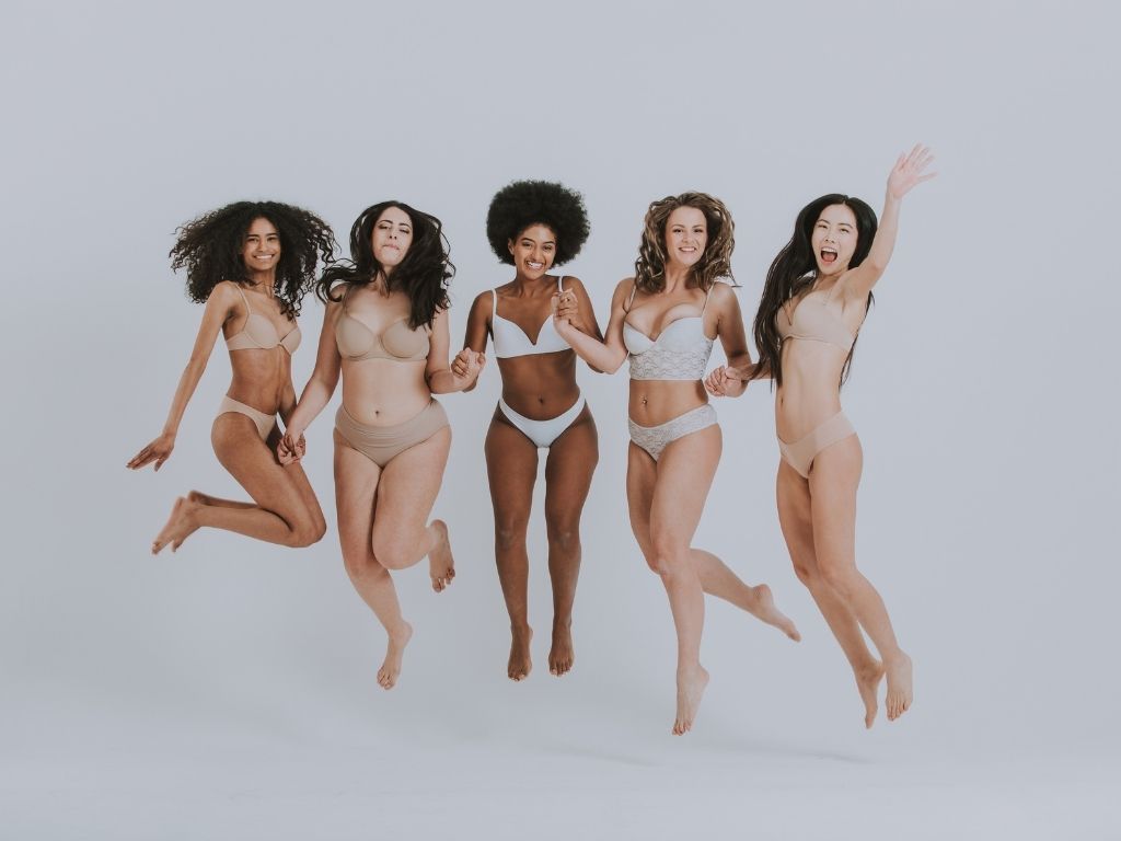 Five women in their underwear jumping and looking happy