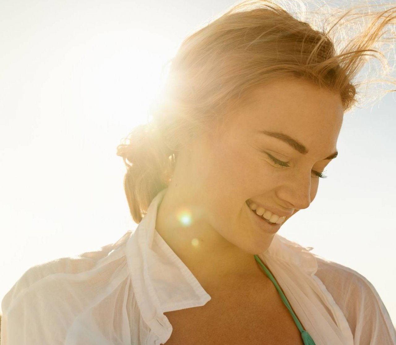 A woman looks at the ground in the sunlight and smiles