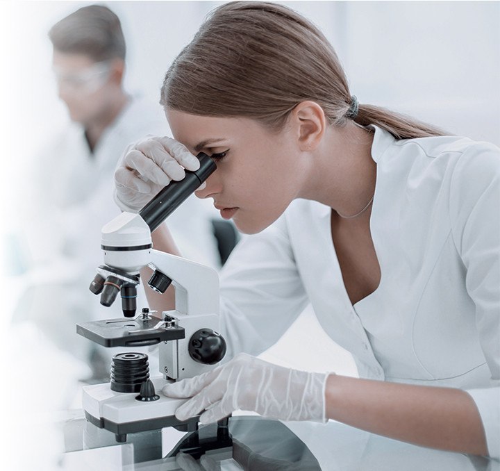 A woman looks into a microscope