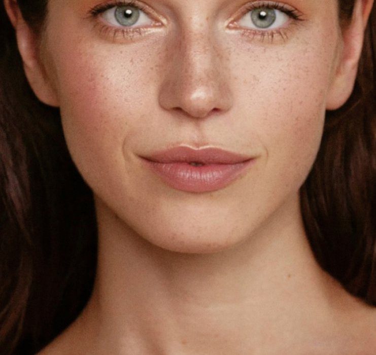 Woman with clear, freckled skin smiles at camera